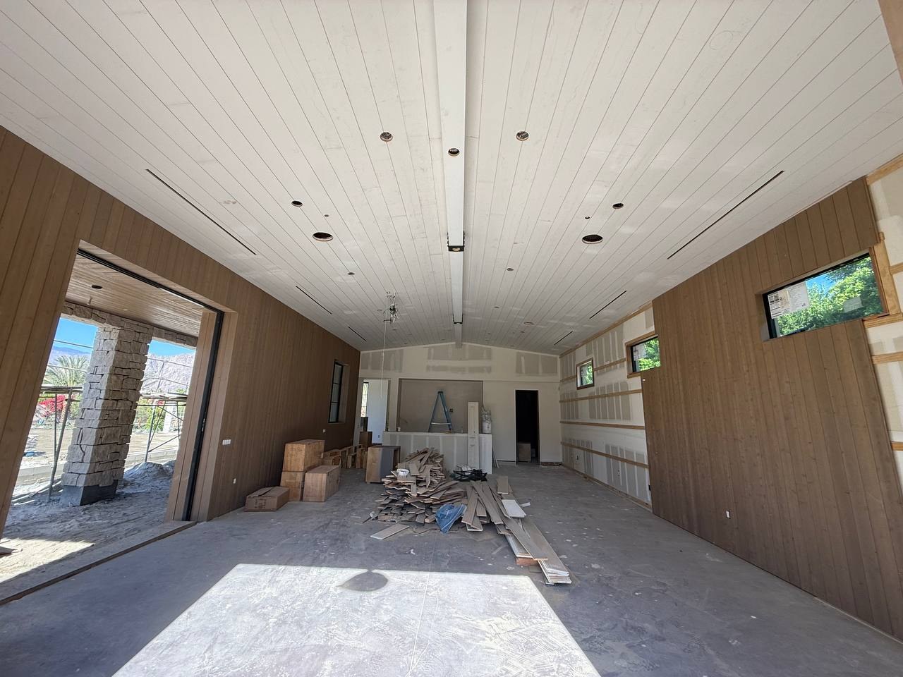 Finished linear slot grilles integrated into the white plank ceiling of a South La Quinta great room