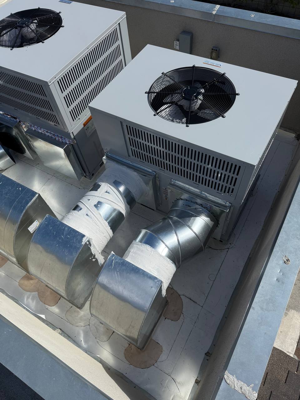 Near-complete installation — both Bosch units on new PVC roof with custom plenums