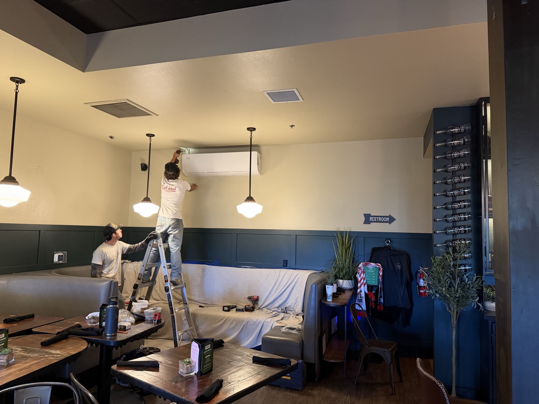 Cal West crew installing a large wall-mounted mini split in a restaurant dining room